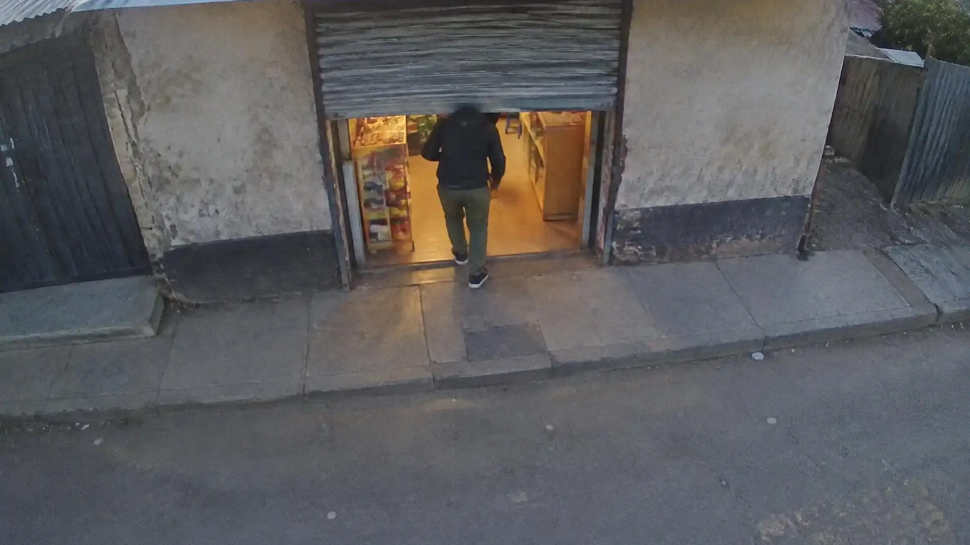 Dusk camera view from above a small shop front with the roller door half down.
